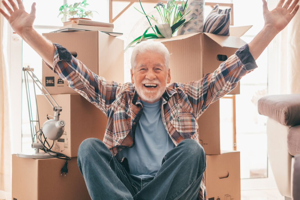 Senior man celebrating in front of moving boxes
